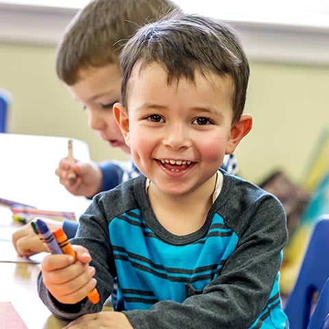 Preschool child holding crayons