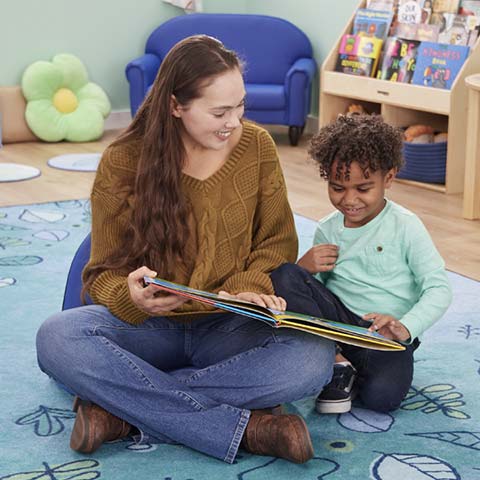 Teacher and preschool child reading a book