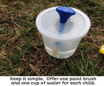 paint brush in container with water for outdoor art activity for preschool