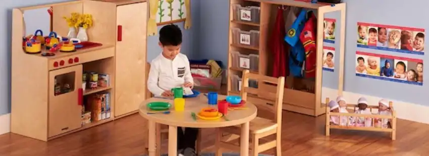 Becker's dramatic play area with kitchen, dress-up storage, and child table for classroom pretend play