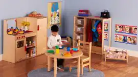 ​​Becker’s dramatic play area with kitchen, dress-up storage, and child table for classroom pretend play​