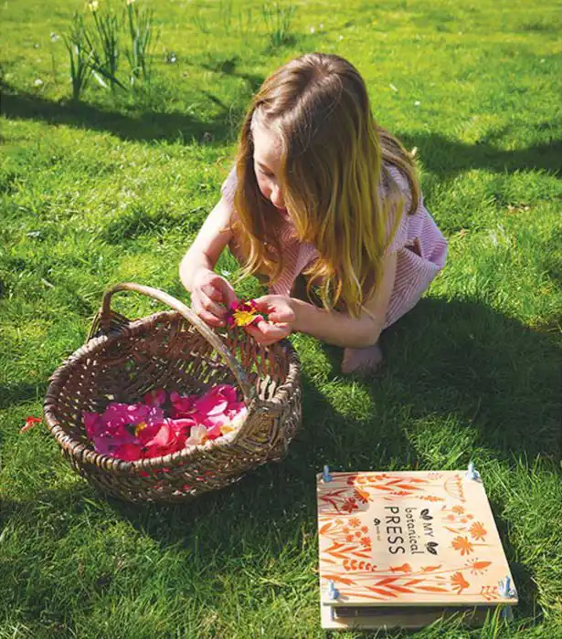 Young girl collecting flowers outdoors for early learning botanical press