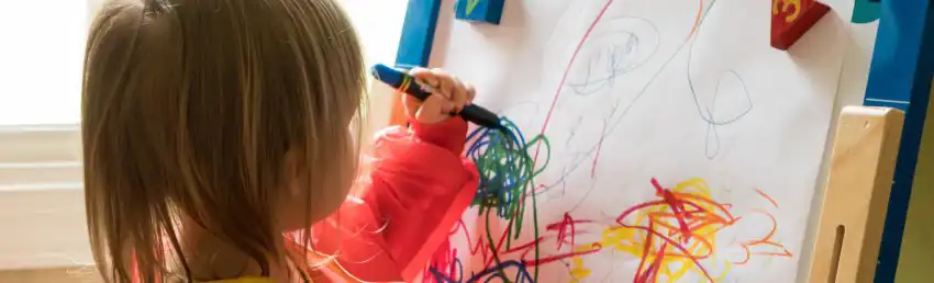 Young girl drawing with markers in an early childhood classroom