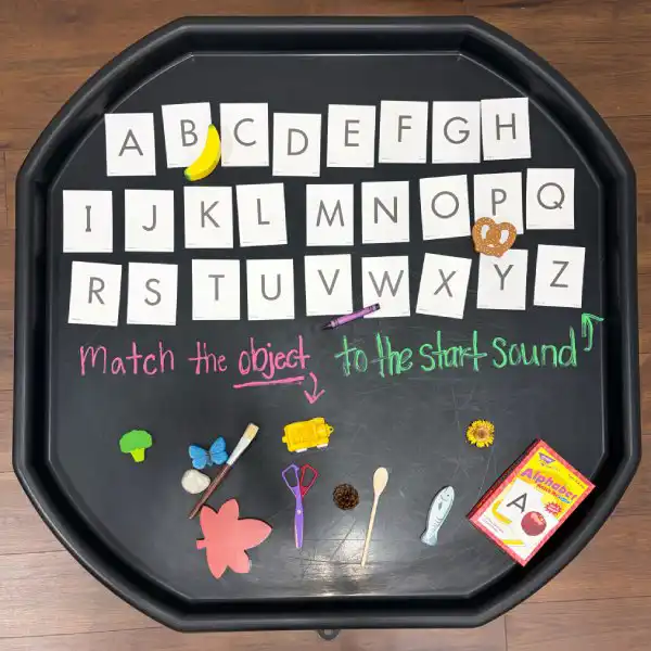 Literacy tuff tray activity that encourages letter recognition and early reading skills.