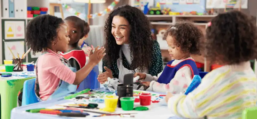 Teacher talking to young children about art creations in preschool classroom