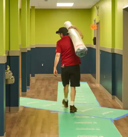Man carrying in rugs for early learning classroom setups