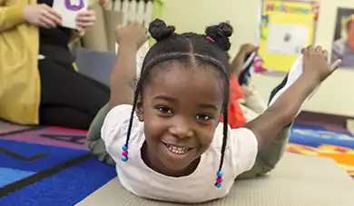 Preschool child practicing yoga on a mat