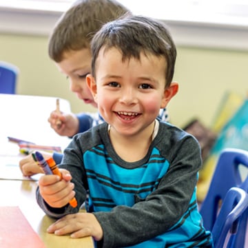 Preschool Boy holding crayons