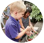 Children outdoors using mud kitchen process cards