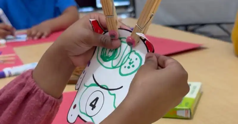 Child holding math monster clothespin learning activity
