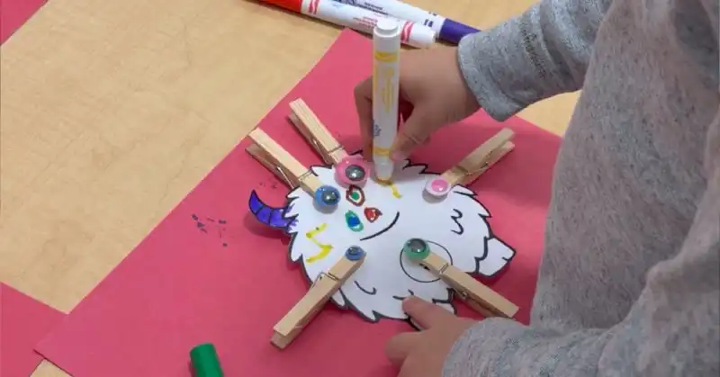 Child coloring math monster activity with clothespin wiggle eyes
