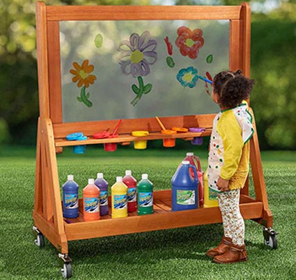 Preschool child painting on outdoor paint wall
