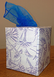 Square tissue box with a blue scarf coming out the top