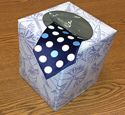 Square tissue box with a blue polka dot coming out the top