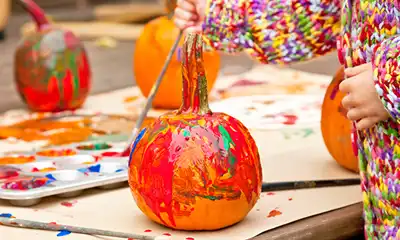 Orange pumpkin being painted by a child