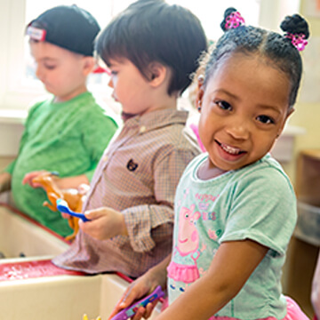 Preschool children playing at sand and water table