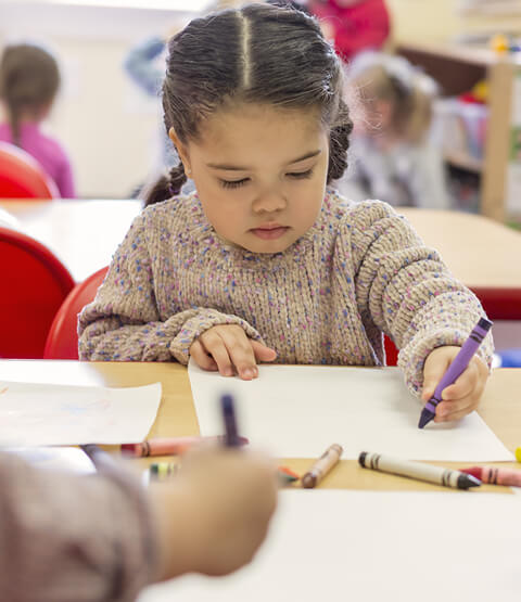 Preschool child sitting at table using crayons from Becker's Students Packs